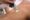 Close up shot of gloved hand with the laser hair removal machine's handpiece along woman leg.