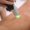 Close up shot of gloved hand with the laser hair removal machine's handpiece along woman leg.