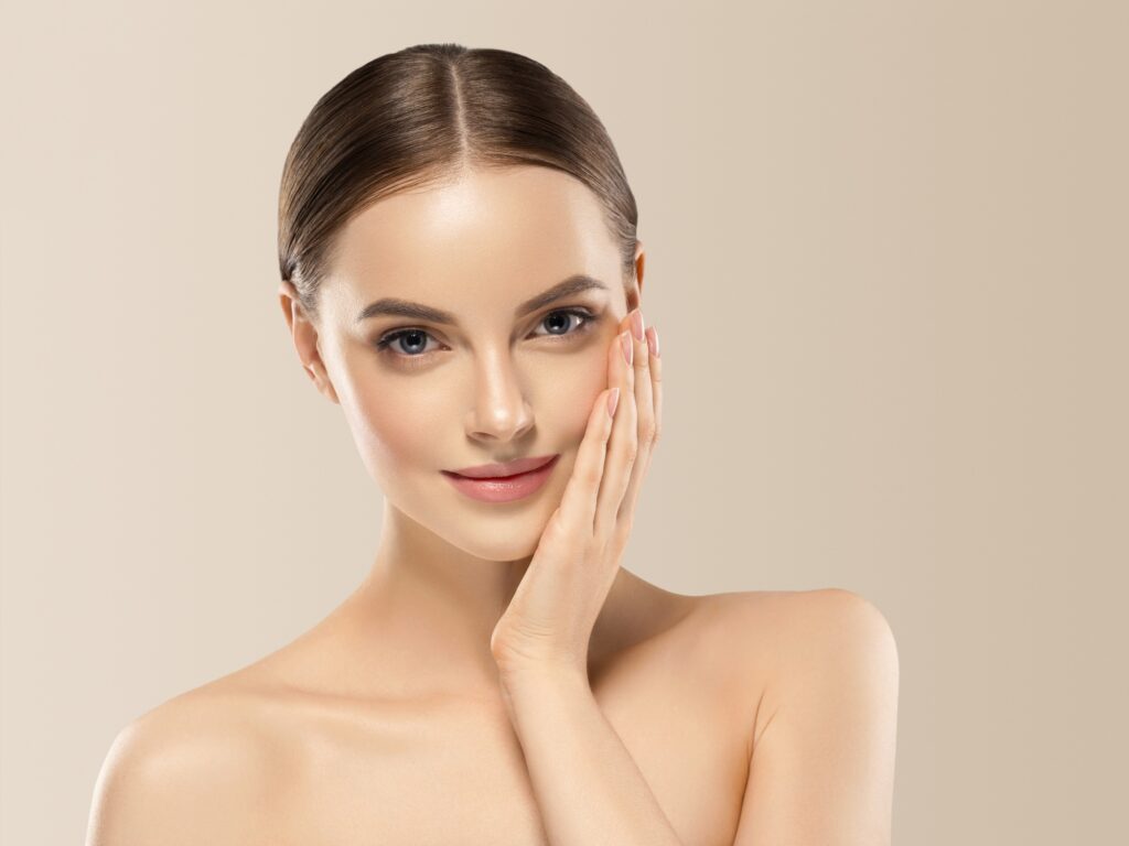 Woman face beauty hand touching face healthy natural makeup female beige background