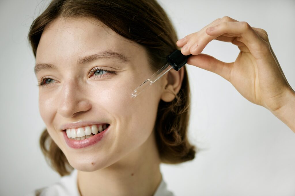 Woman Smiling Widely While Using Face Serum