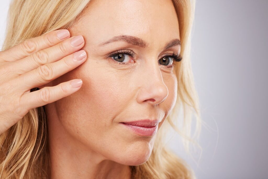 Face, skincare and antiaging with a mature woman in studio on a gray background for natural beauty.
