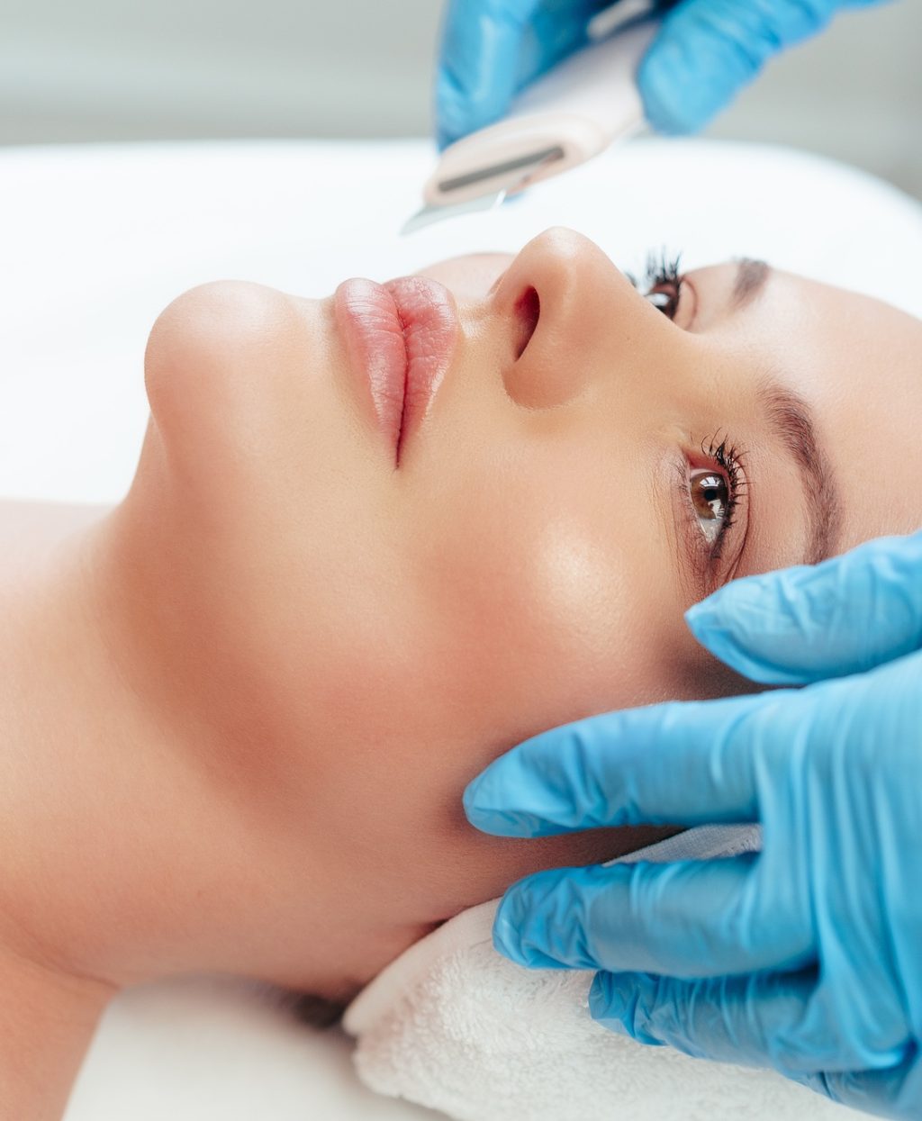 Beautiful woman receiving ultrasonic face cleaning in beauty salon