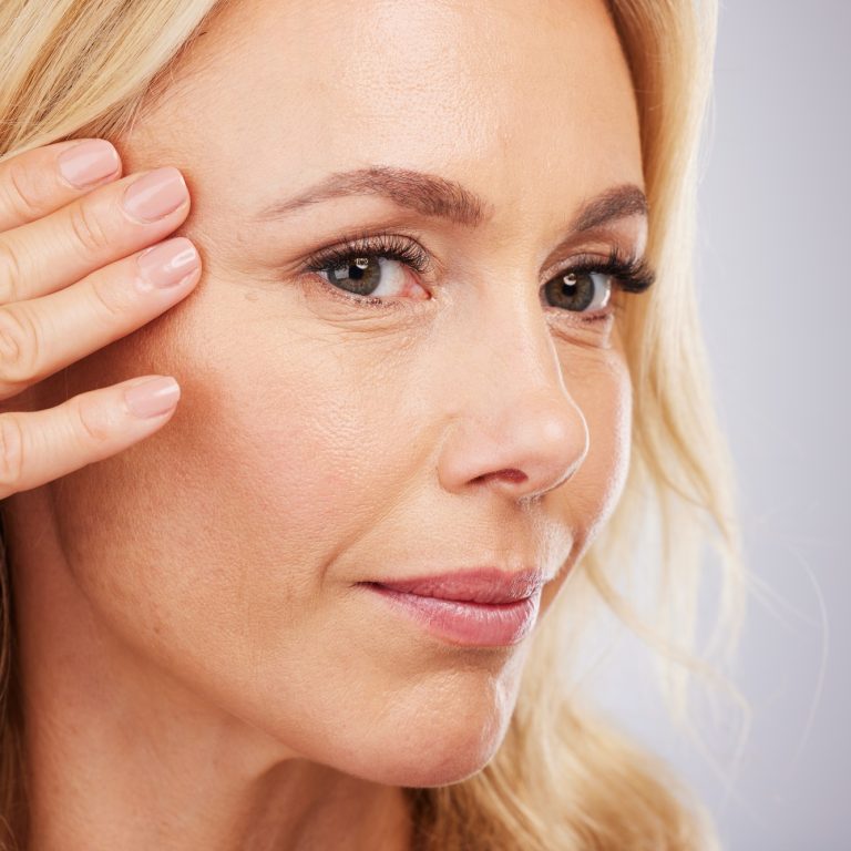 Face, skincare and antiaging with a mature woman in studio on a gray background for natural beauty.