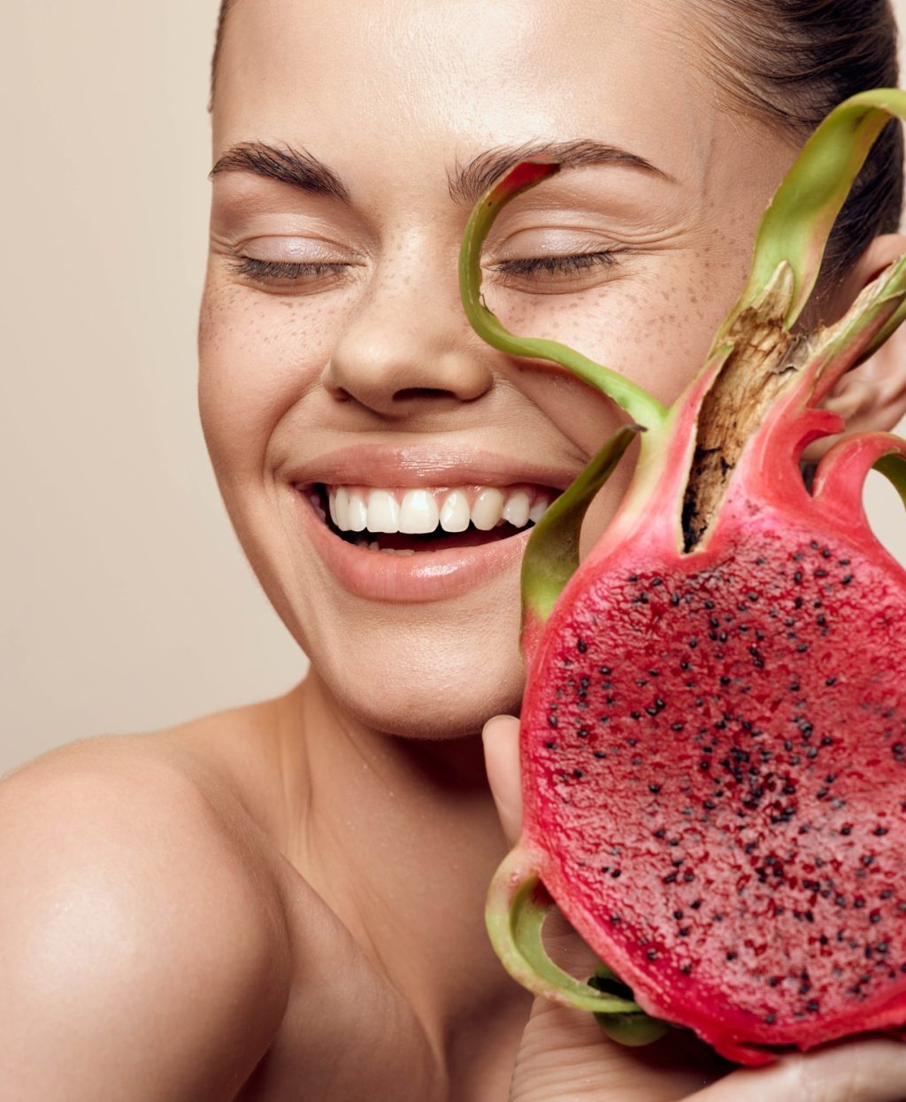 Smiling woman holding exotic dragon fruit in front of face tropical fruit concept